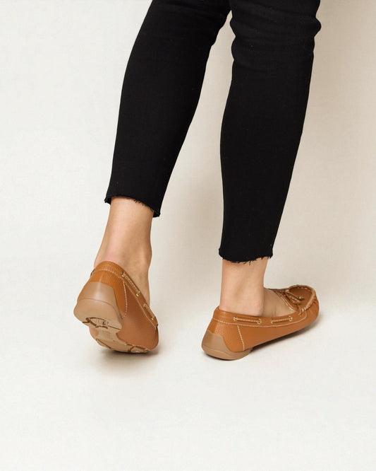 Brown loafers worn with black pants on a white background