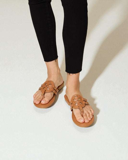 Brown sandals worn with black pants on a plain background