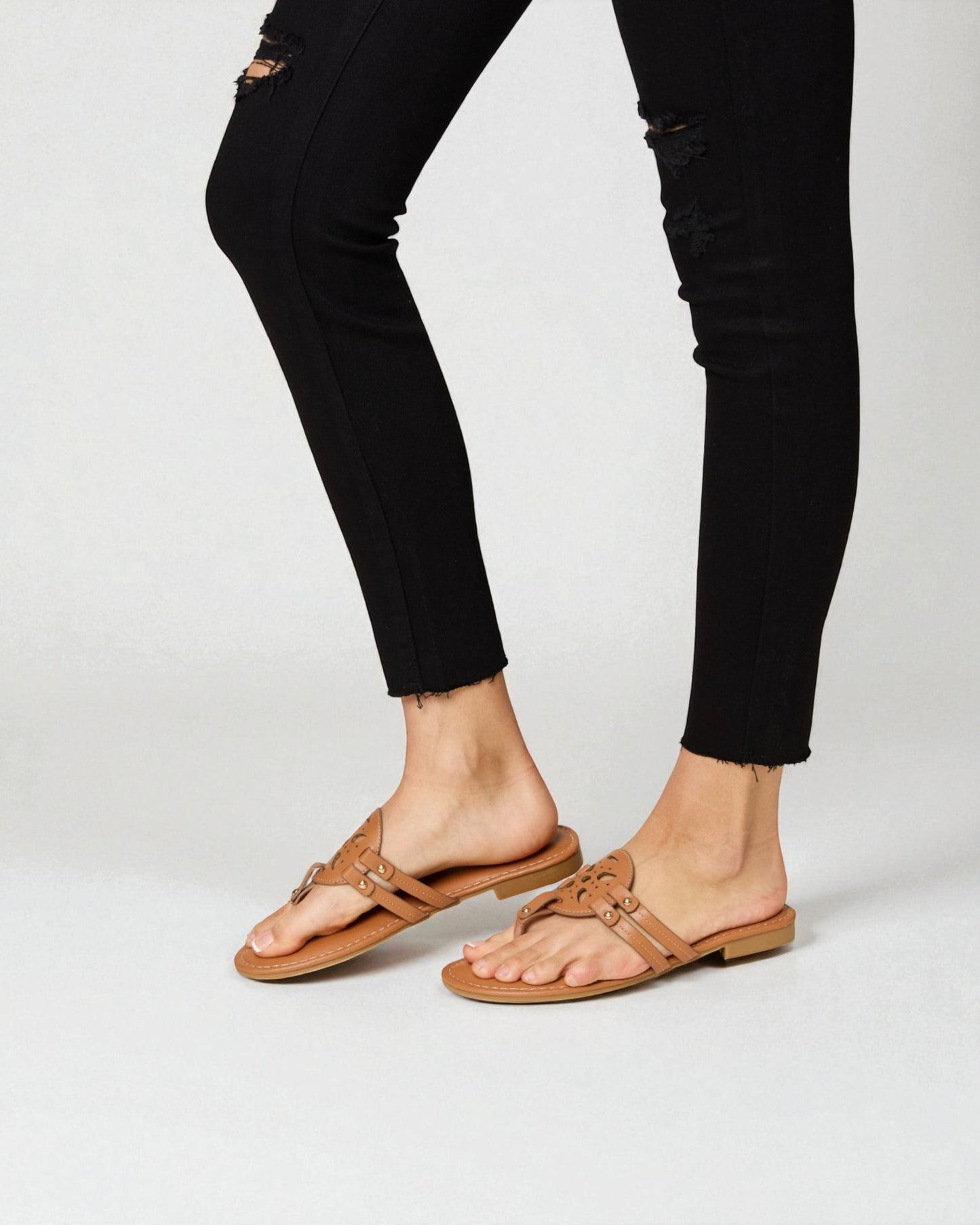 Person wearing brown sandals with black pants on a white background