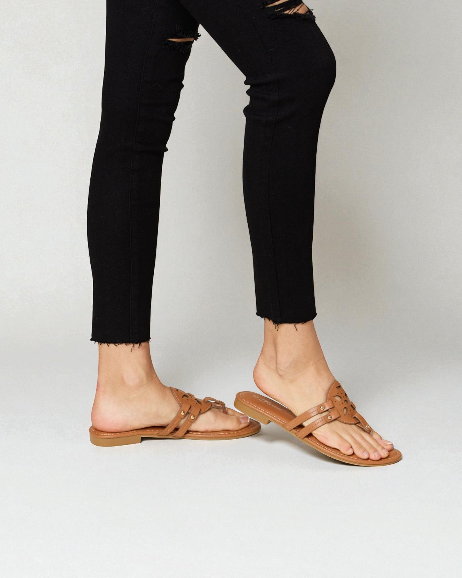 Person wearing black pants and brown sandals on a white background