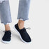 Black sneakers worn with light blue jeans on a white background