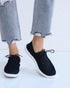 Black sneakers worn with light blue jeans on a white background