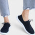Navy blue sneakers with white soles worn with light blue jeans on a white background