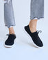 Black sneakers worn with light blue jeans on a white background