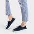 Black sneakers worn with ripped jeans on a light background
