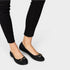Black flats worn with black pants on a white background
