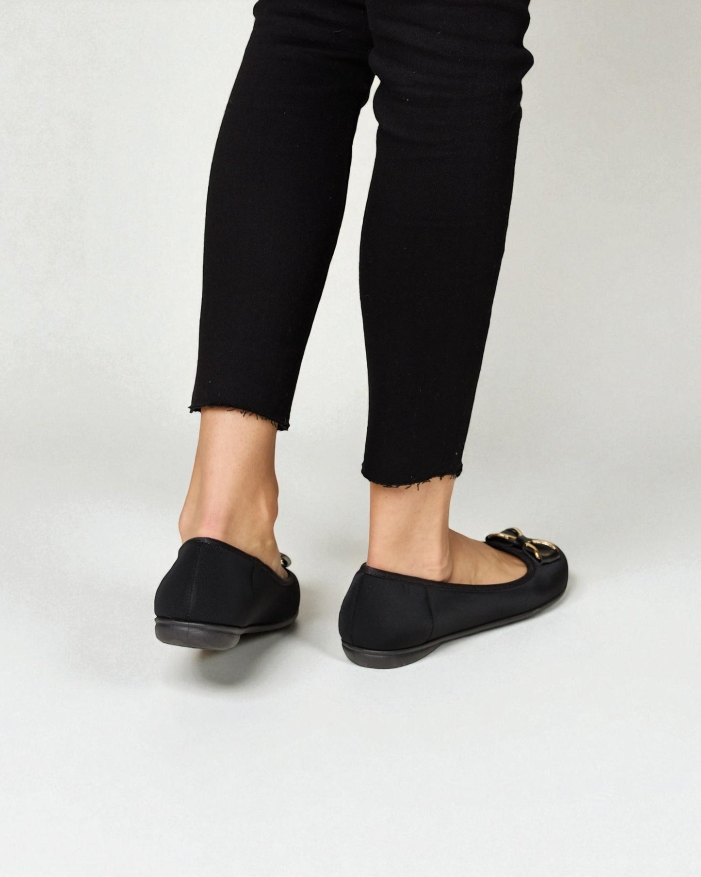 Person wearing black loafers and black pants on a white background