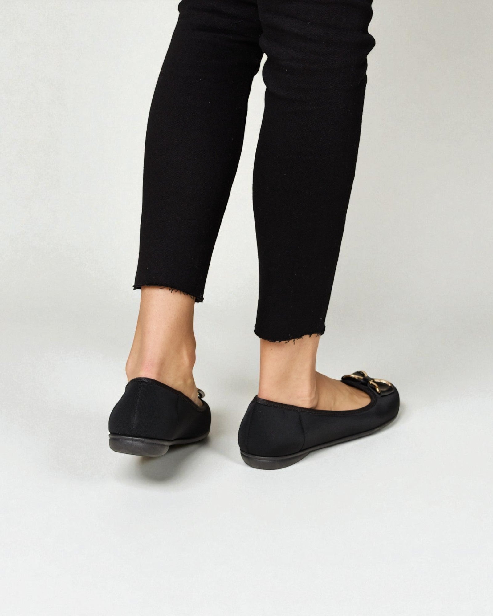 Person wearing black loafers and black pants on a white background