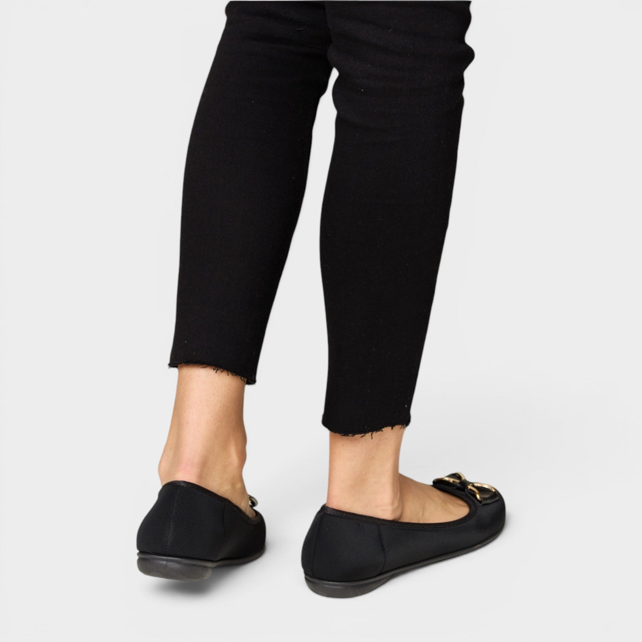 Black loafers worn with black pants on a white background