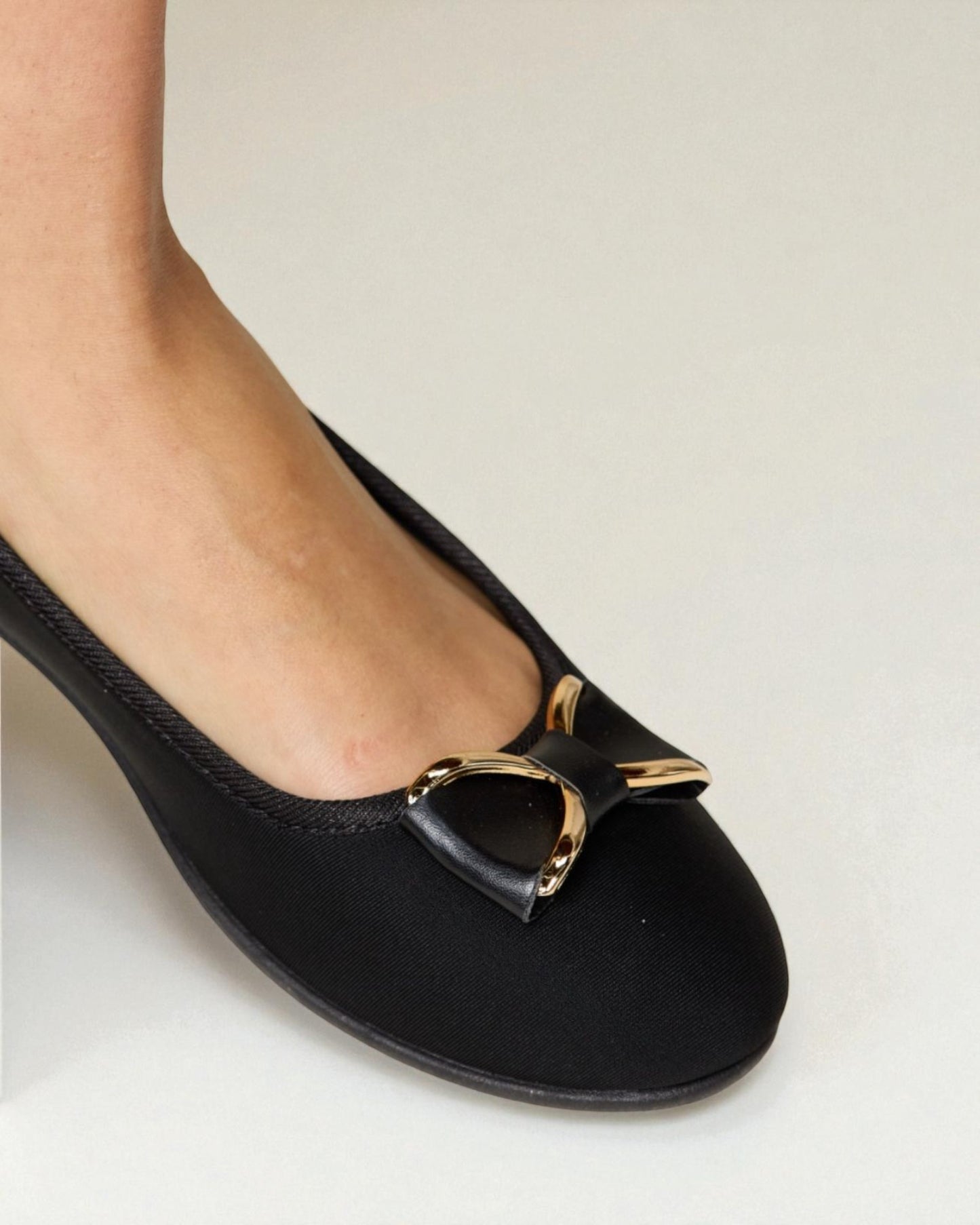 Black flat shoe with a gold buckle on a white background
