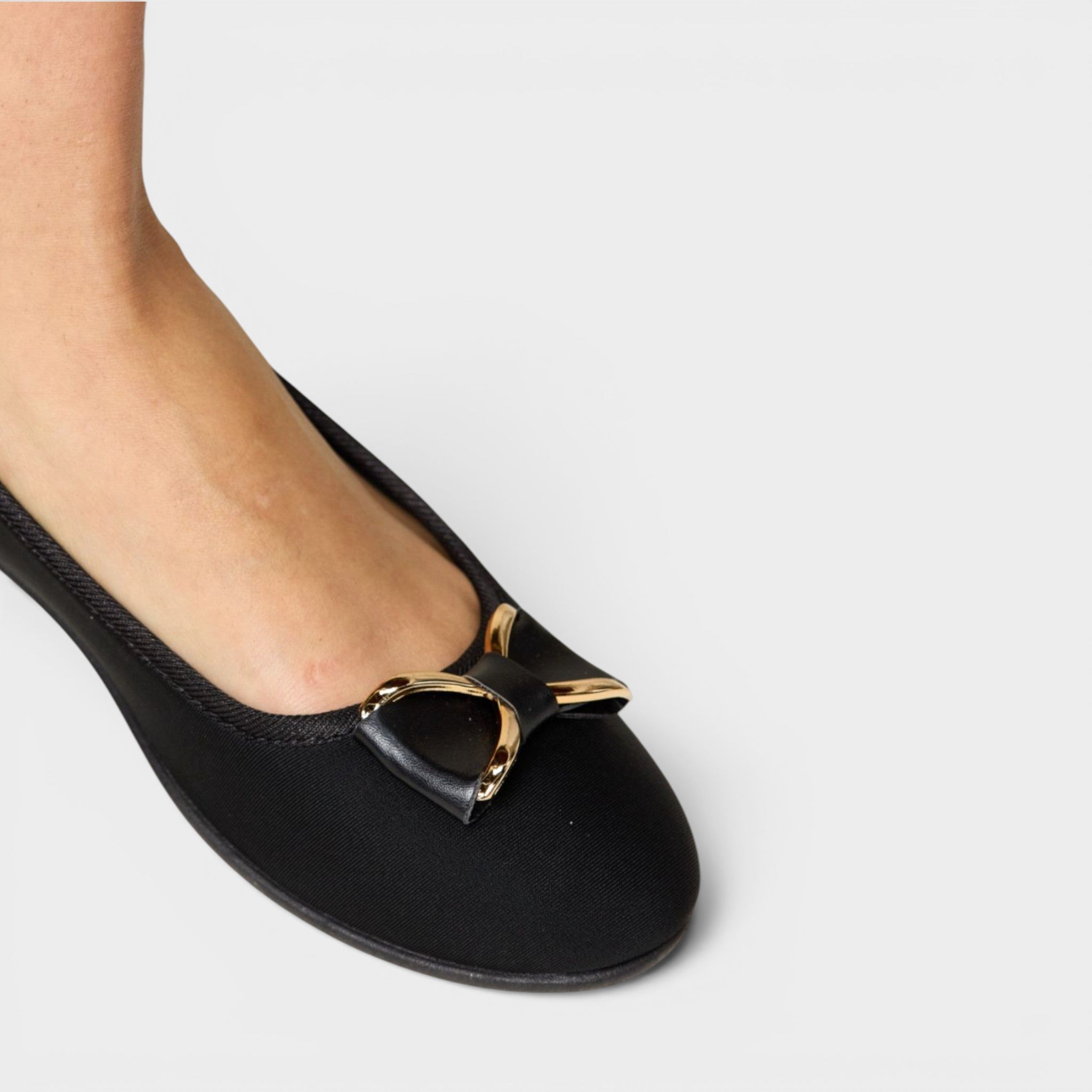 Black flat shoe with a gold buckle on a white background