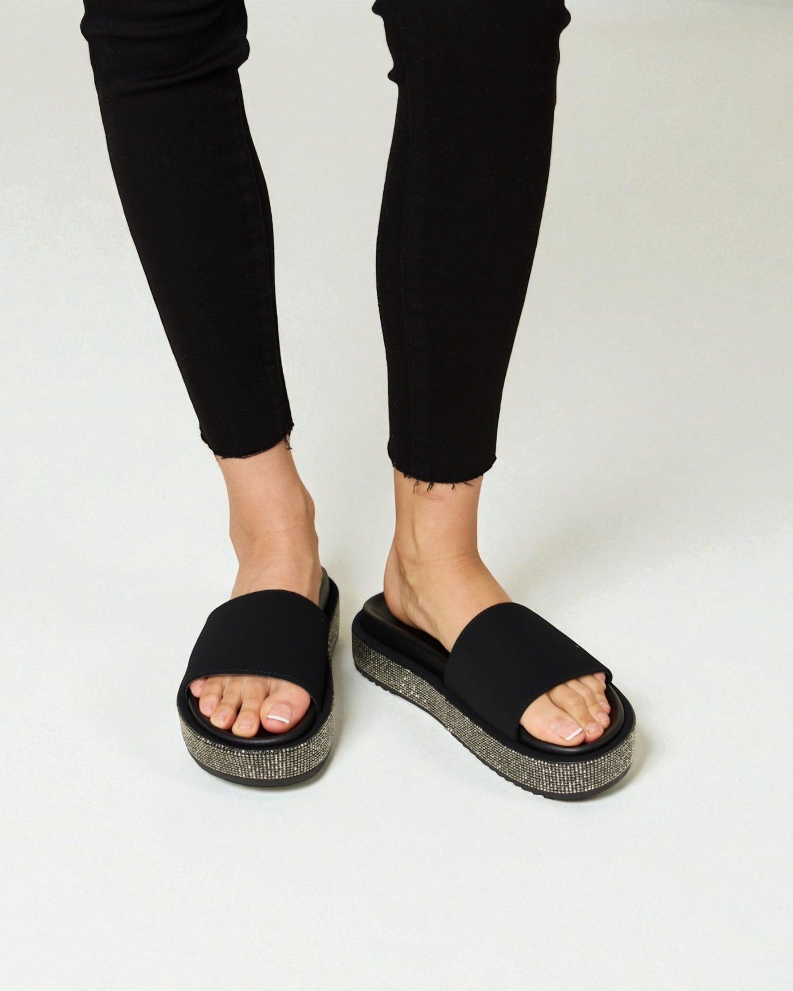 Person wearing black sandals with a textured sole on a white background