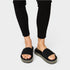 Black sandals worn with black pants on a white background