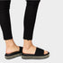 Black sandals with glittery sole worn with black pants on a light gray background