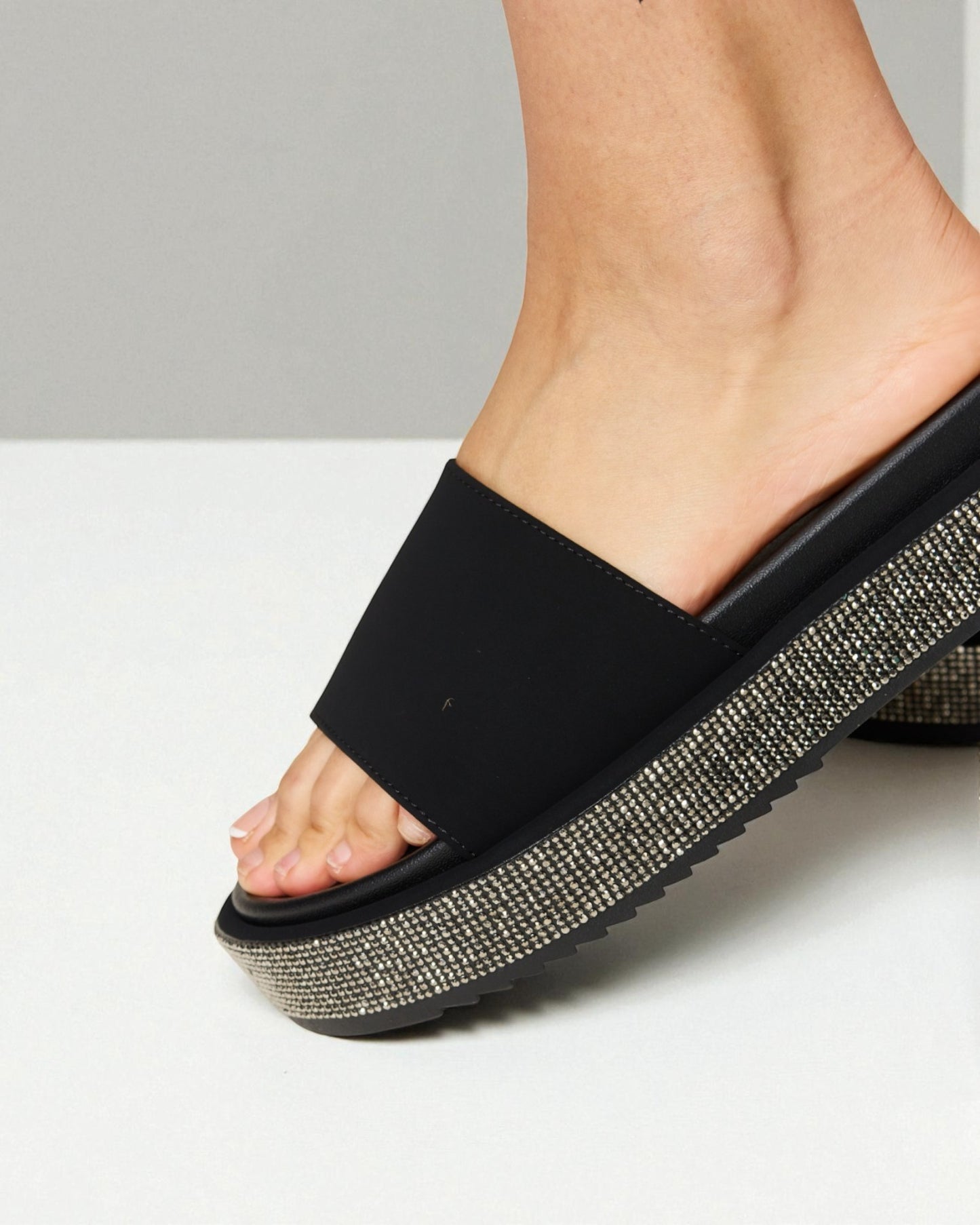 Black slide sandal with rhinestone sole on a white background