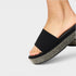 Black sandal with a textured sole on a light gray background