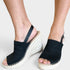 A pair of women's black knit wedge sandals with espadrille-style woven soles, shown being worn on a person's feet against a light gray background.