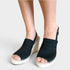 A pair of women's black woven espadrille wedge sandals with open toes, shown on a model's feet against a light gray background.