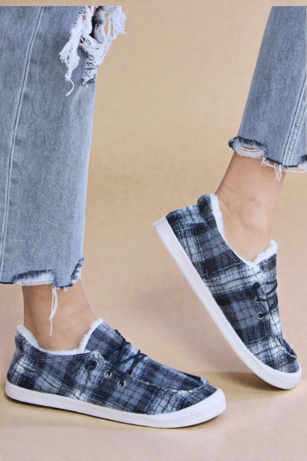 Blue plaid sneakers with white soles worn with ripped jeans on a beige background