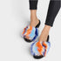 Colorful tie-dye slippers worn with black pants on a white background
