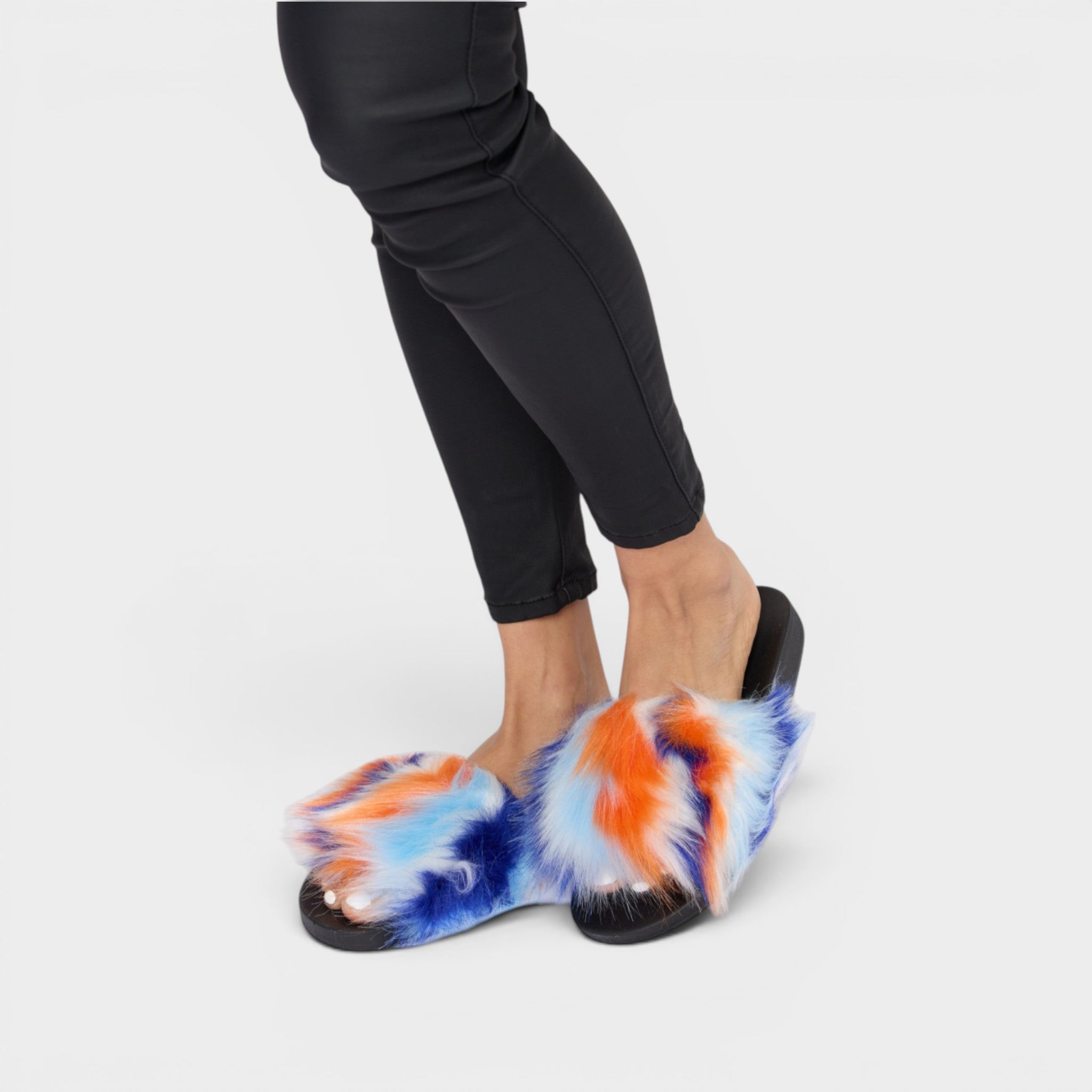 Person wearing colorful tie-dye slippers on a plain background