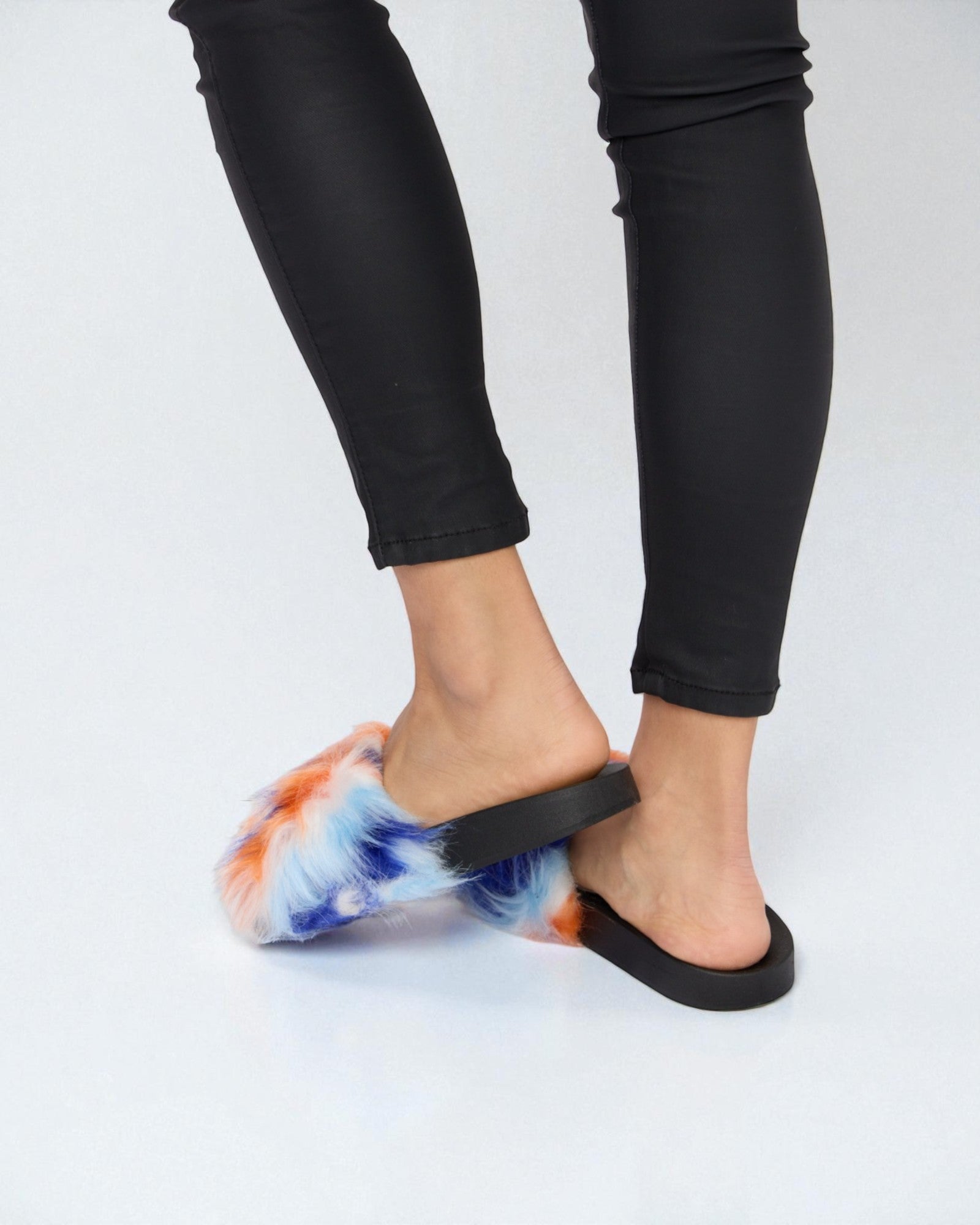 Person wearing tie-dye sandals with black straps on a white background