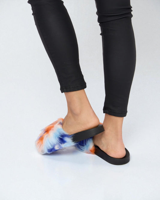 Person wearing tie-dye sandals with black straps on a white background