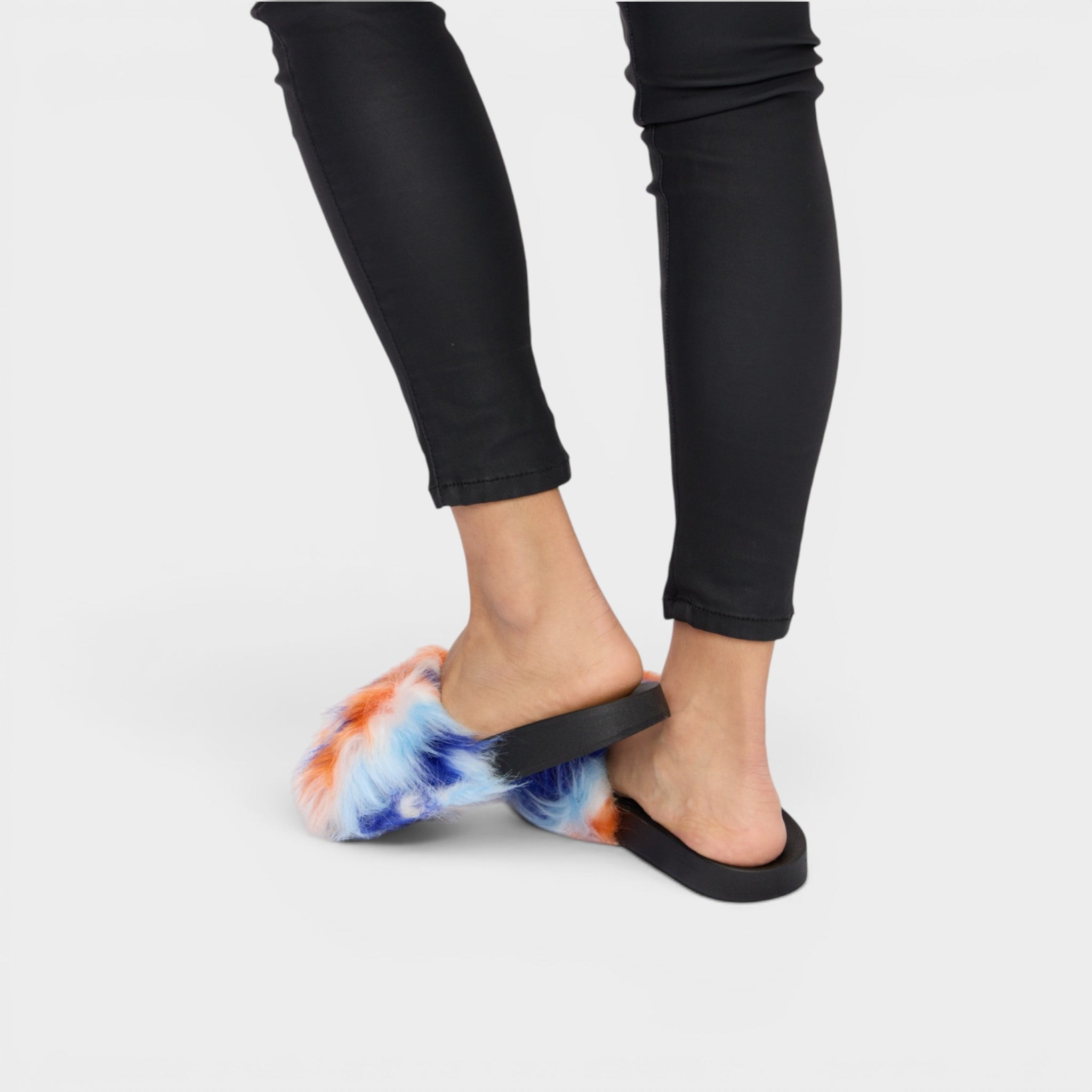 Person wearing tie-dye sandals with black straps on a white background