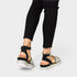 Black sandals with glittery sole worn with black pants on a light gray background