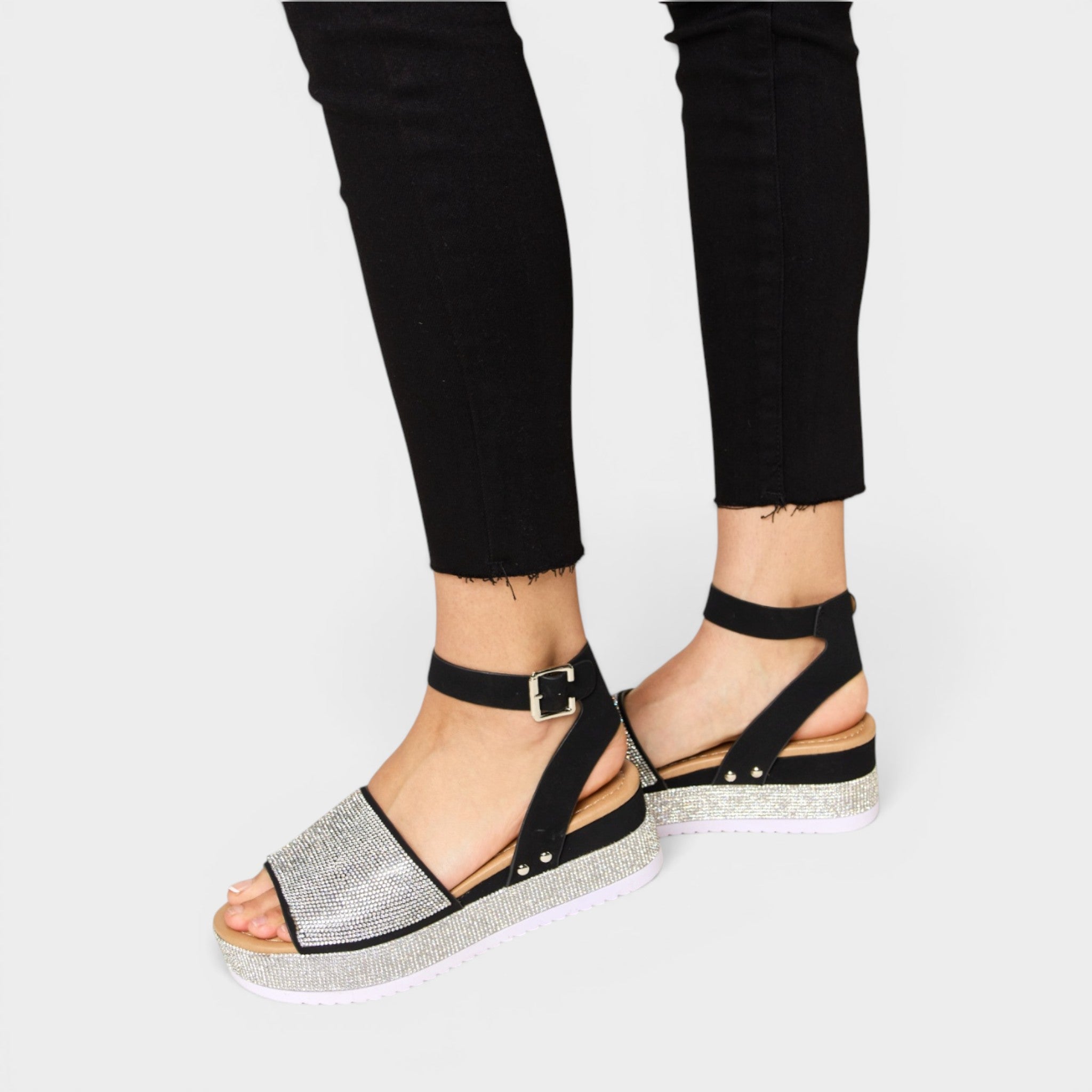 Black sandals with silver glittery sole worn with black pants on a white background