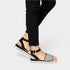 Black strappy sandal with a platform sole worn with black pants on a light gray background
