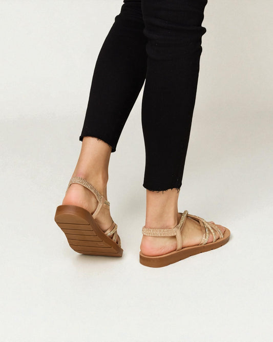 Person wearing beige sandals with a white background