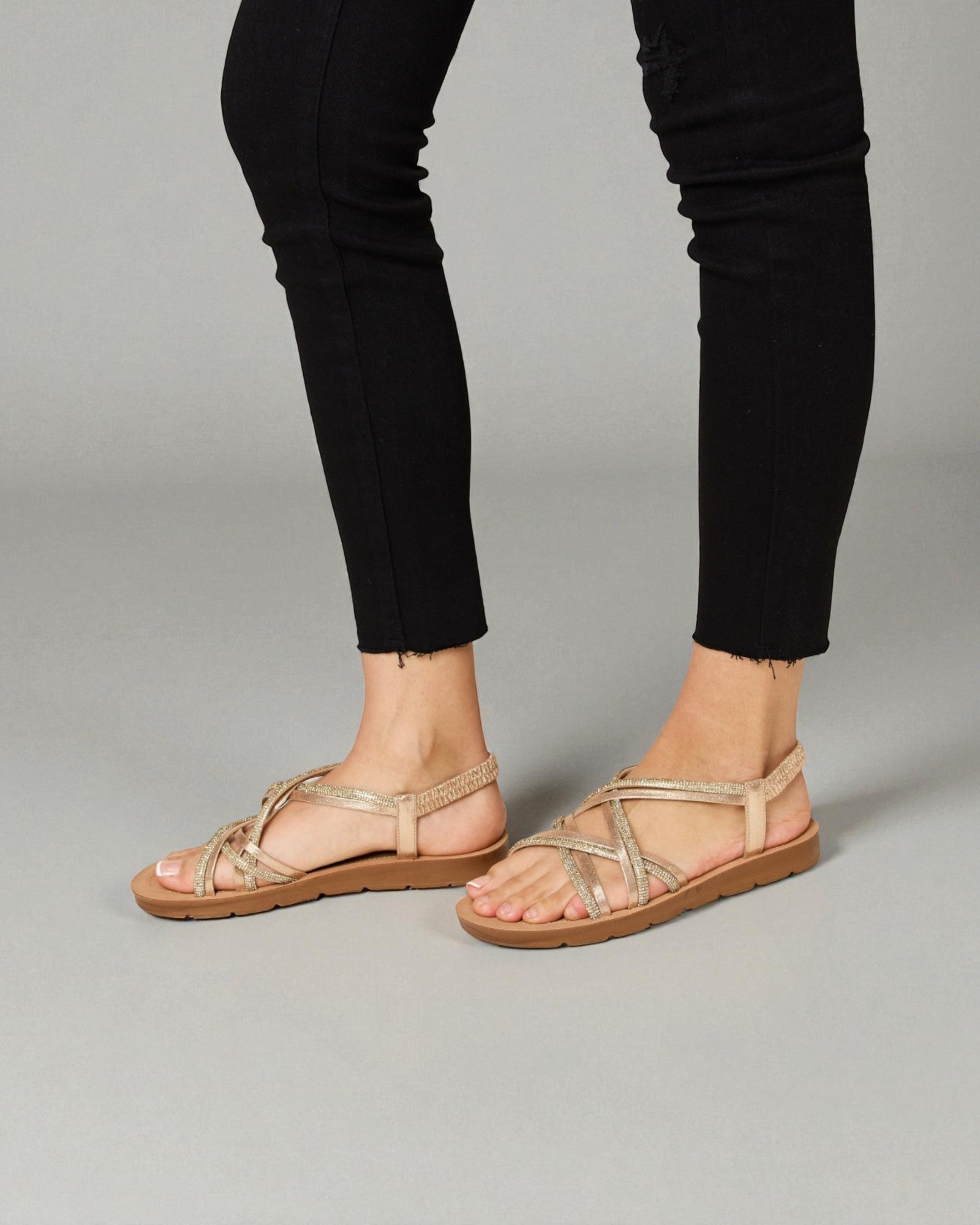 Beige sandals worn with black pants on a gray background
