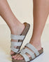 Silver sandals with cork sole worn by a person on a light background