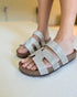 Silver sandals with cork sole worn by a person on a light background