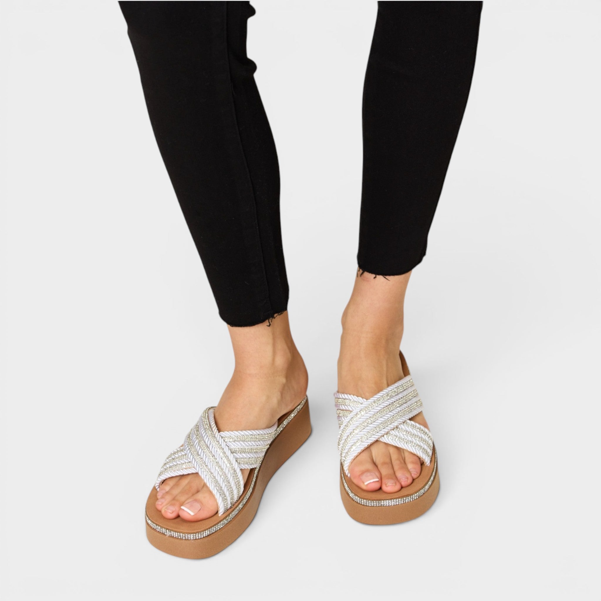 White sandals with brown soles worn by a person on a white background