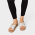 White sandals with brown soles worn by a person on a white background