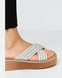 White sandal with brown sole worn by a person on a white background