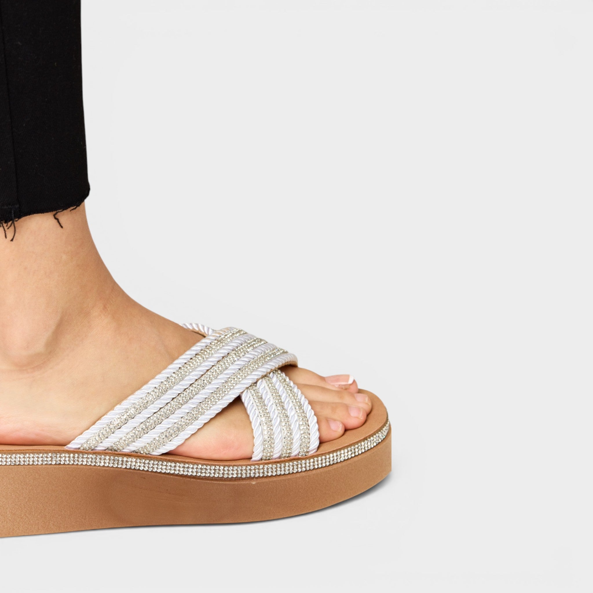 Beige sandal with criss-cross strap design on a white background