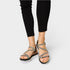 Black sandals with thin straps worn by a person on a white background