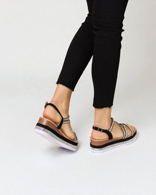 Person wearing black sandals with white soles on a light gray background