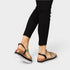 Person wearing black sandals with straps on a light gray background