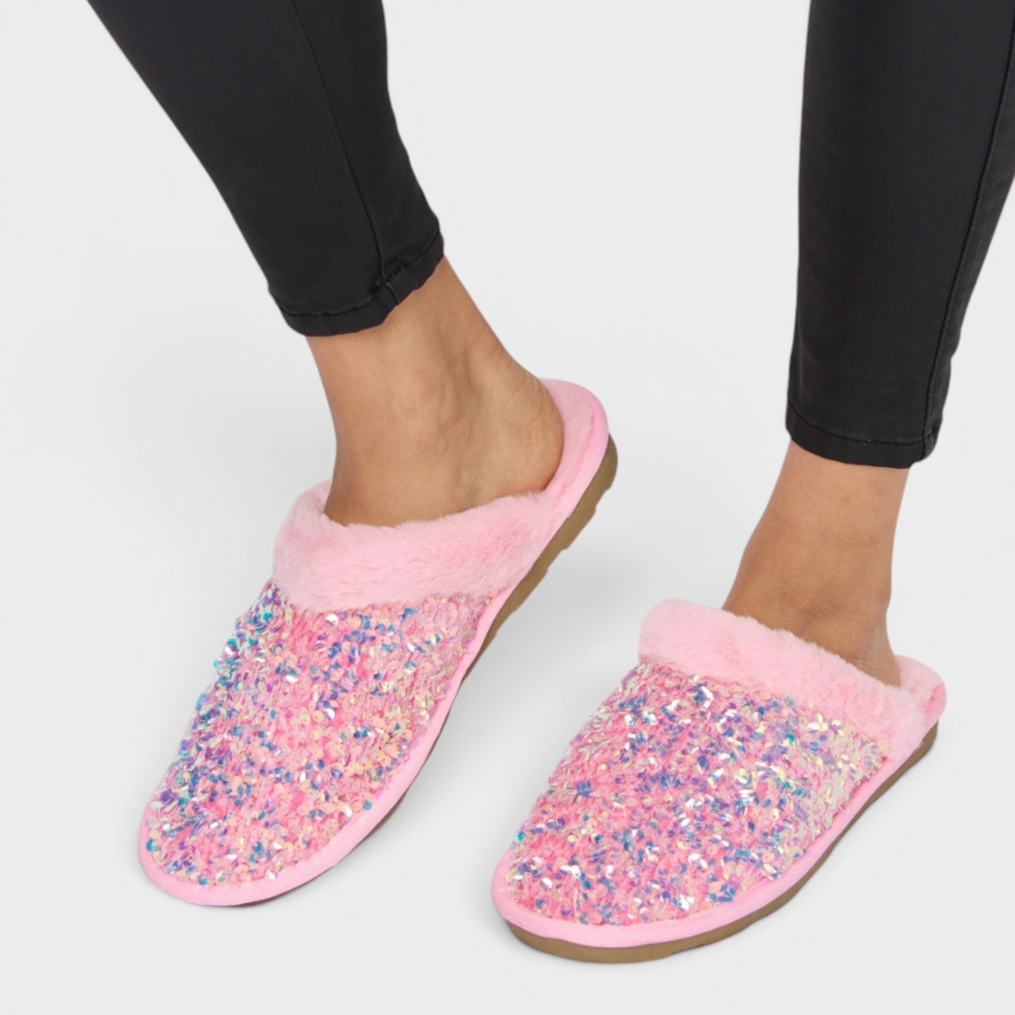 Pink slippers with glitter sole worn by a person on a white background