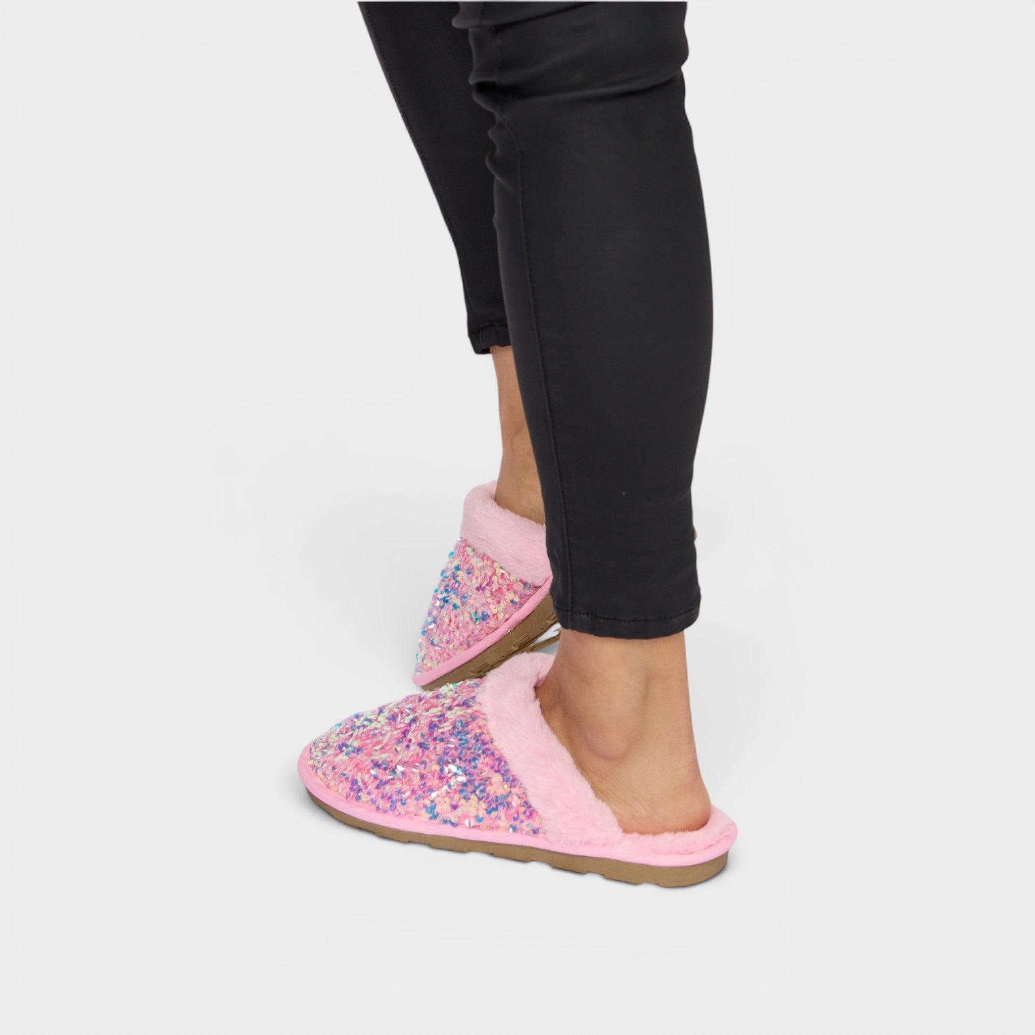 Pink slippers with floral pattern worn by a person on a white background