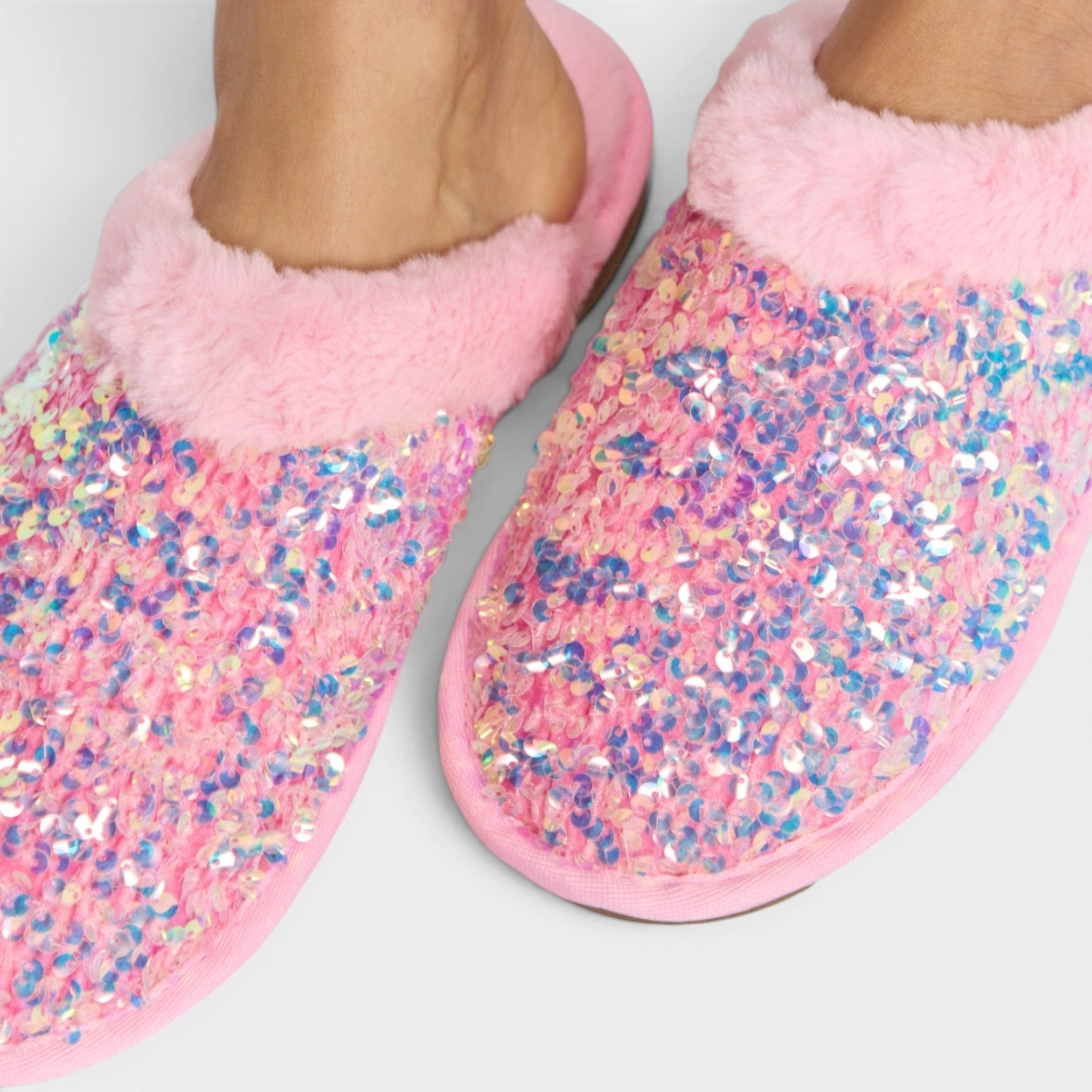 Pink glittery slippers worn by a person on a light gray background