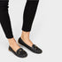 Black loafers worn with black pants on a light gray background