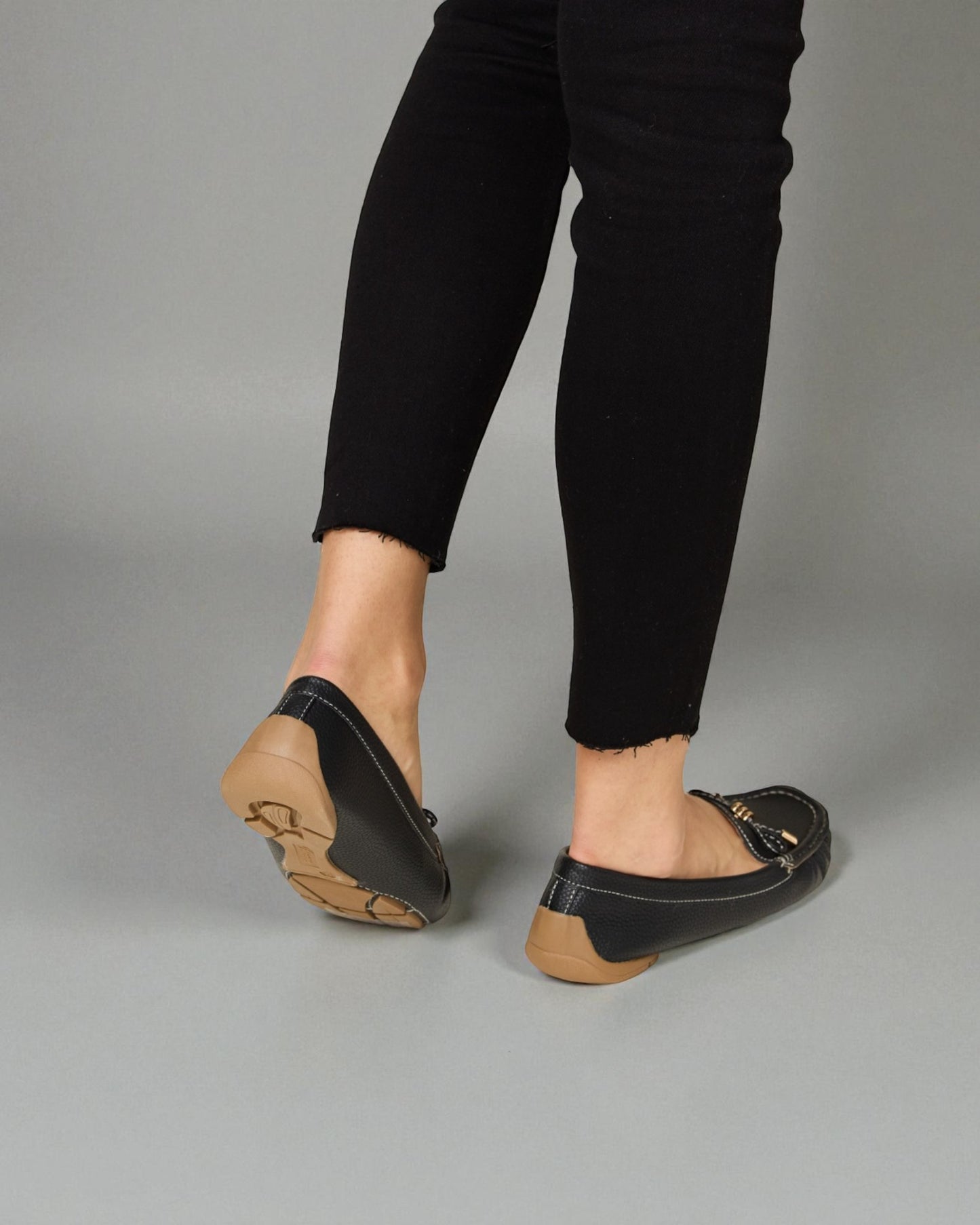 Person wearing black loafers on a gray background
