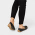 Black flat shoes worn with black pants on a white background