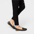 Black flat shoes worn with black pants on a white background