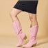 Pink knee-high boots worn with a black skirt on a beige background